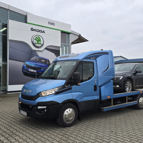 Servicii tractări auto Focșani - platforma Iveco cu mașină neagră încărcată în oraș